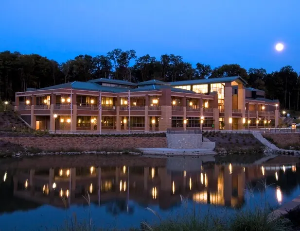 Anderson Center brick building lit up at dusk, reflected in a pond under a full moon