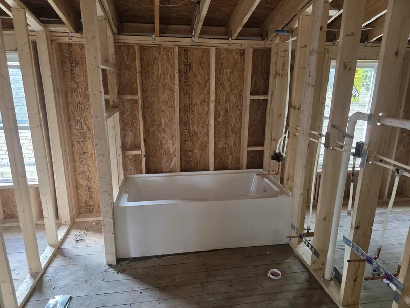 New bathtub set in an open-framed bathroom during rough-in plumbing