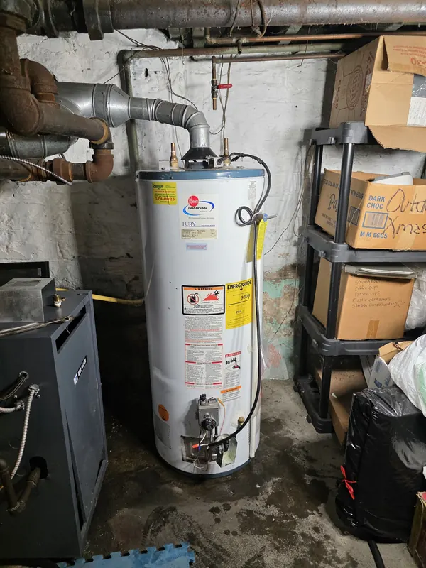 Old gas tank water heater in a basement before replacement