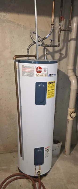 Old Rheem electric tank water heater in a basement before replacement