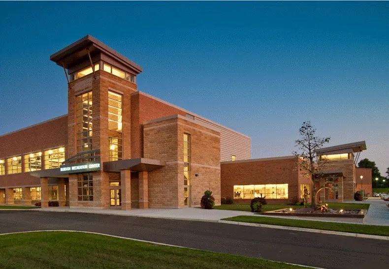 Blue Ash Recreation Center, a brick and stone building with a lit glass tower entrance at dusk