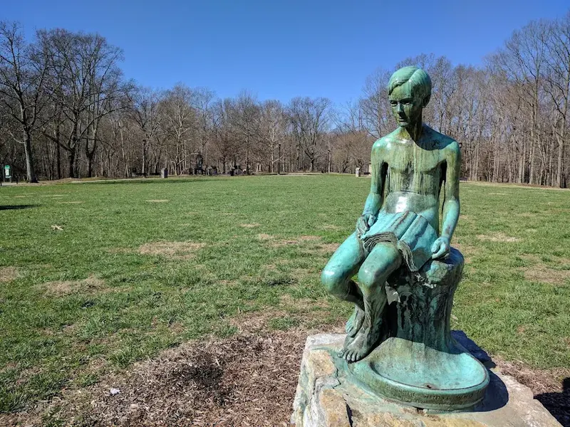 Bronze statue of a seated boy in an open park field in Mount Washington