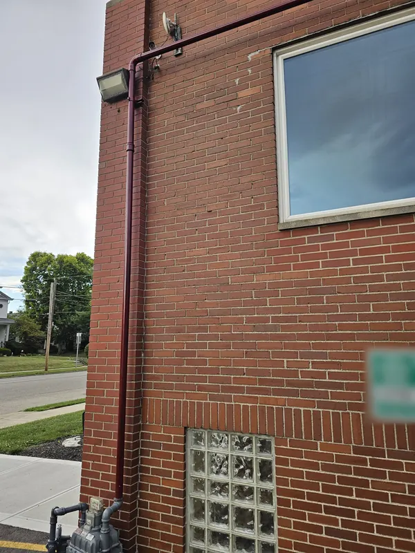 Commercial gas line rising from the gas meter up the brick wall of a church