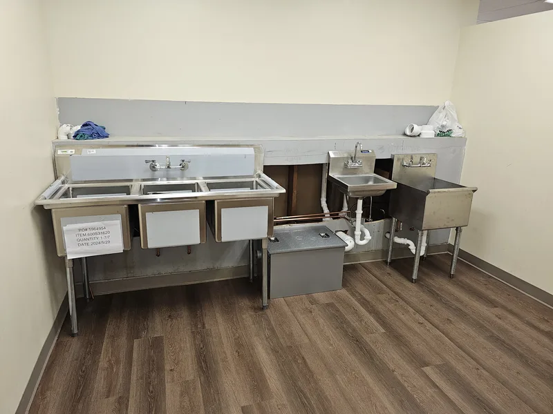 New commercial sink line with a stainless three-compartment sink, hand sink and mop sink on a wood-look floor