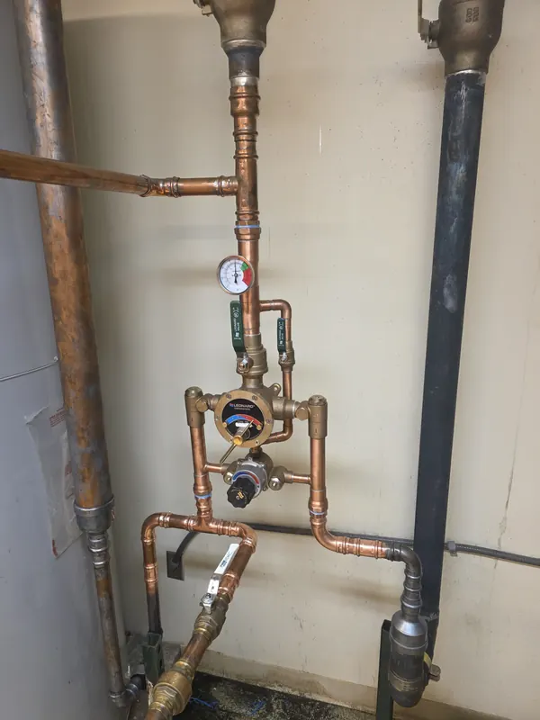 Leonard thermostatic mixing valve with a temperature gauge on new copper piping in a commercial mechanical room