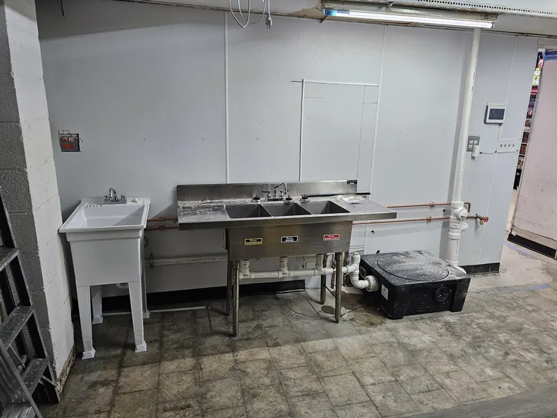 Stainless three-compartment sink, mop sink and hand sink installed in a commercial kitchen