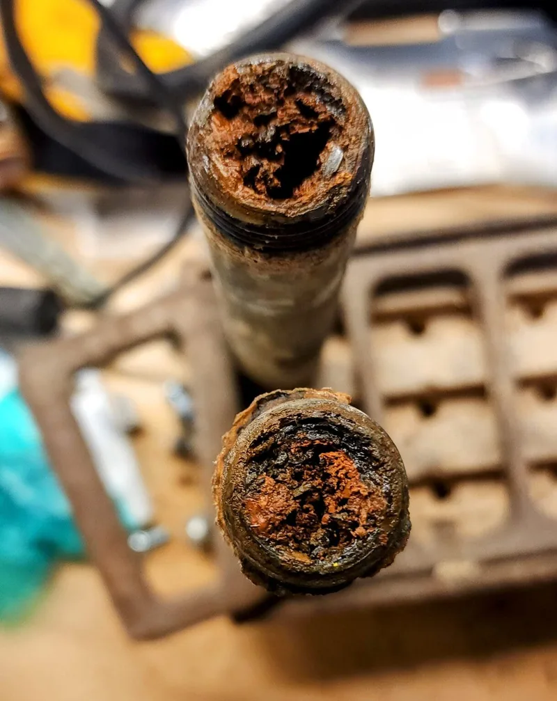 Two cut galvanized pipe ends heavily corroded and rusted inside, nearly closed off