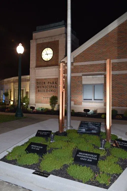 Deer Park Municipal Building at night with its clock and a 9/11 memorial garden