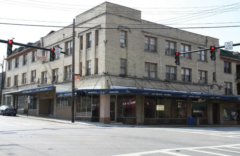 Three-story tan brick corner building with blue storefront awnings and traffic lights in downtown Cheviot