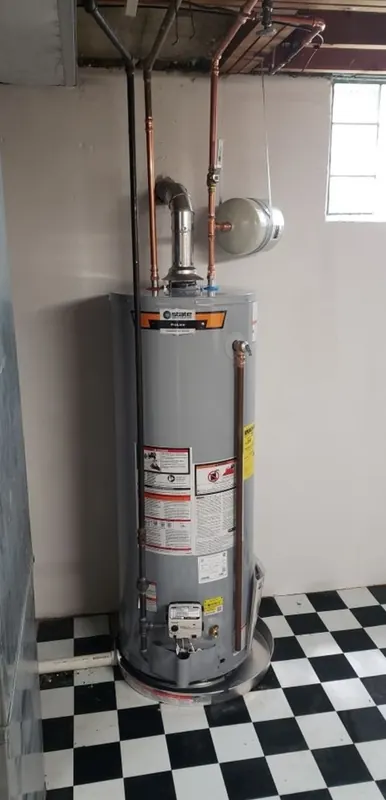 New gas tank water heater with expansion tank installed on a checkered basement floor