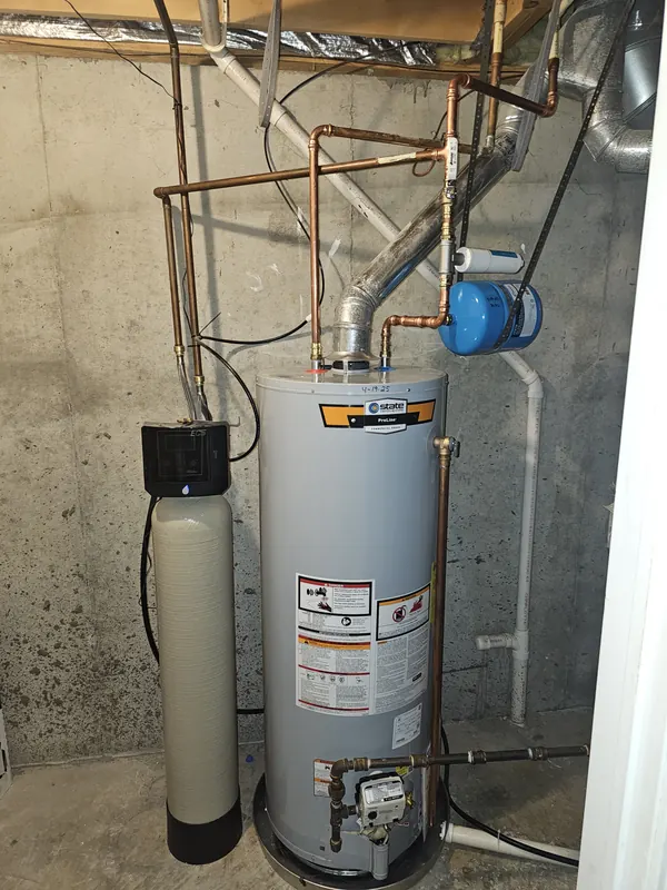 Gas tank water heater with new copper piping beside a water softener tank