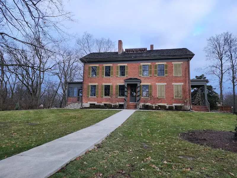 Hunt House, a red brick historic house with green shutters on a grassy hill in Blue Ash