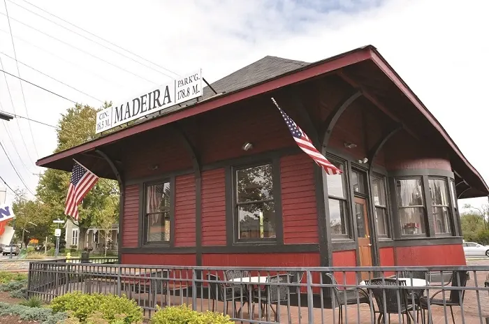 Red Madeira train depot with American flags and a fenced patio