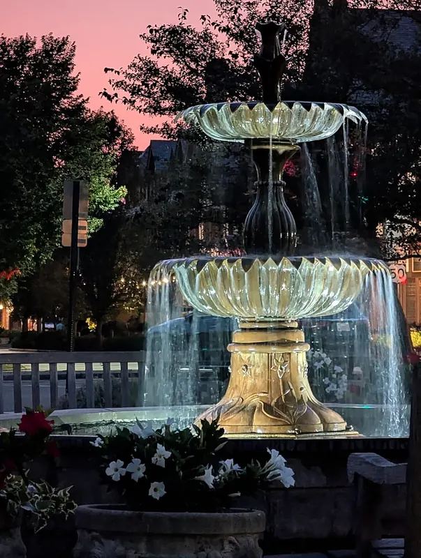 Lit tiered fountain with white flowers at sunset in Mariemont