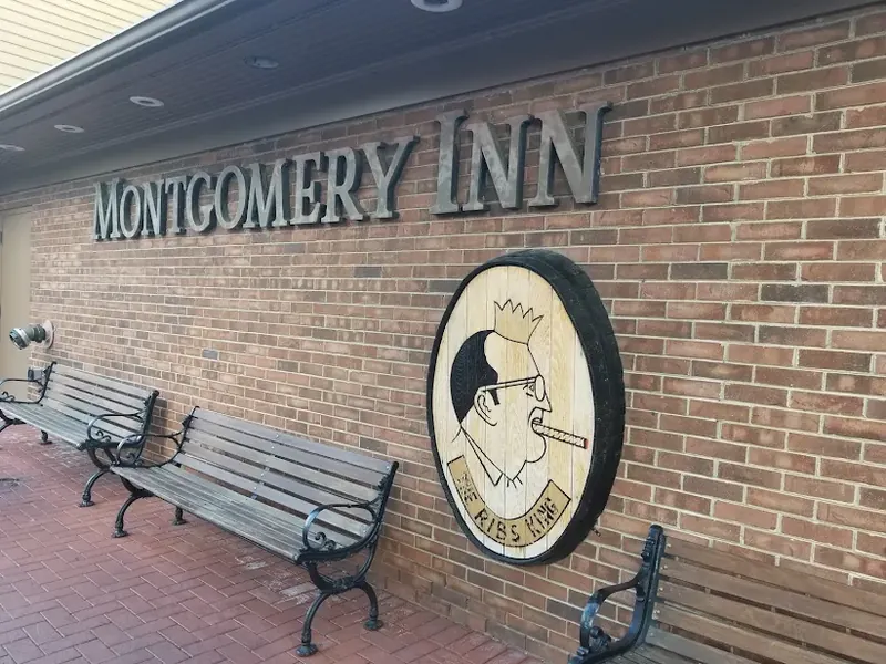 Montgomery Inn sign on a brick wall above wooden benches