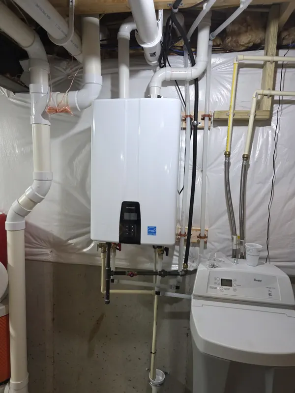 Navien tankless water heater installed on a basement wall next to a water softener