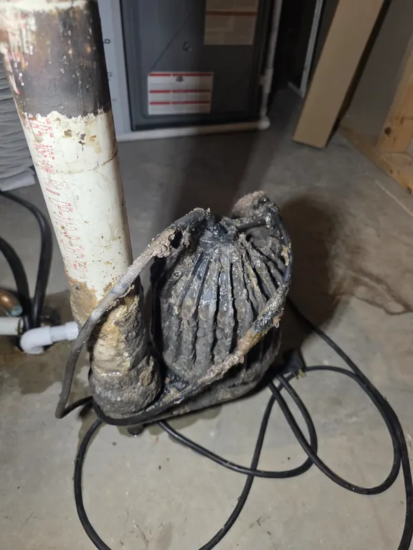 Old sewage pump caked with buildup, removed from its basin in a basement