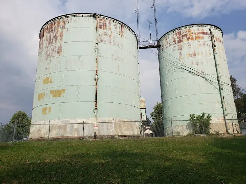Two old weathered water storage tanks on a grassy hill in Norwood
