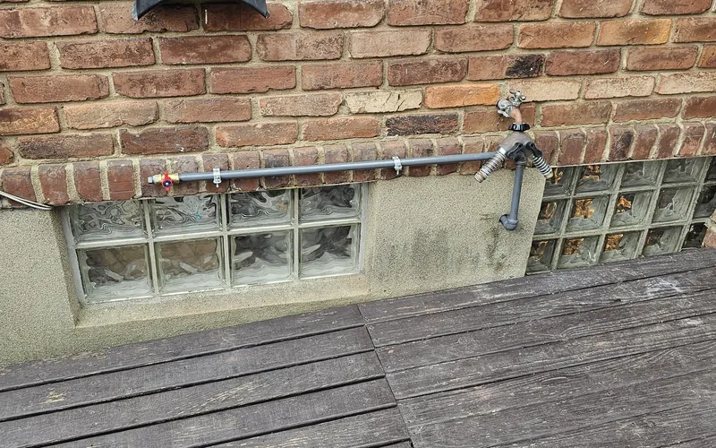 Gas line run along a brick wall to a deck for an outdoor grill