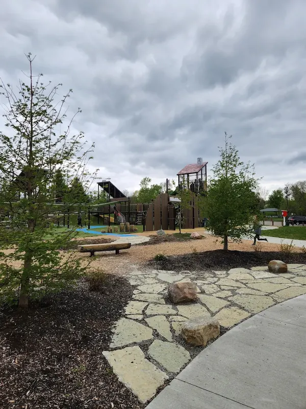 Park playground with a stone path and young trees in Colerain Township