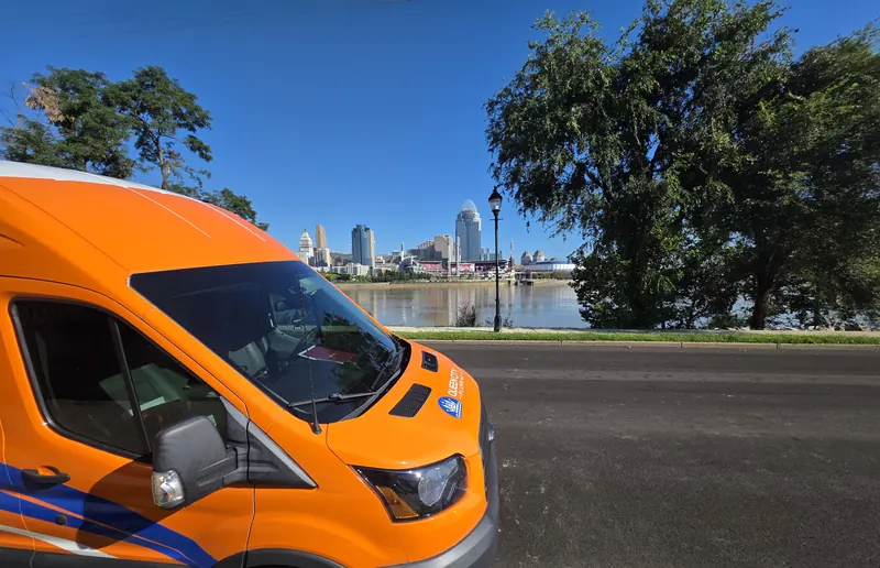 Queen City Plumbing service van parked along the Ohio River with the Cincinnati skyline behind