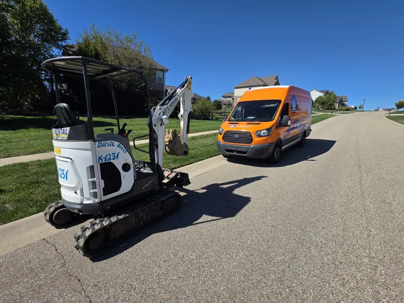Queen City Plumbing service van parked on a street beside a rented mini excavator for digging work