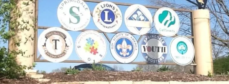 Sign with emblems of Springdale service organizations, including Lions, Scouts and Girl Scouts