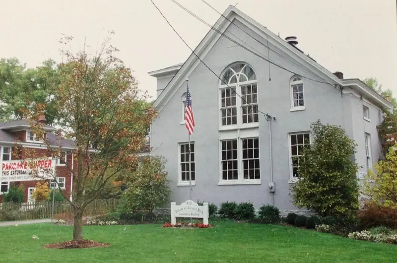 Gray Village of Terrace Park Community Building with an American flag and a lawn sign out front