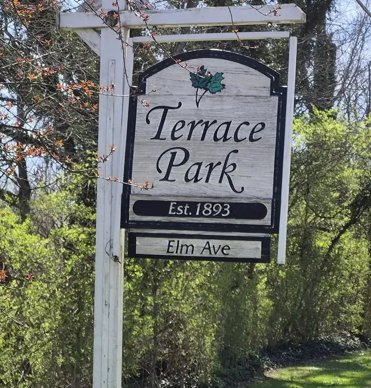 Wooden Terrace Park Est. 1893 sign on a post above an Elm Ave street sign