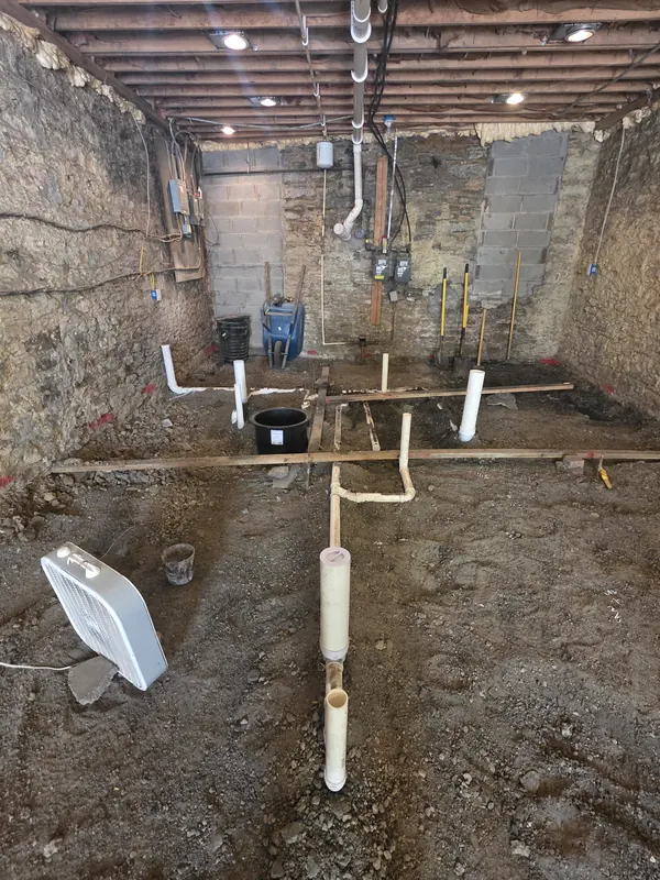 New PVC underground drain lines laid in an open basement floor trench