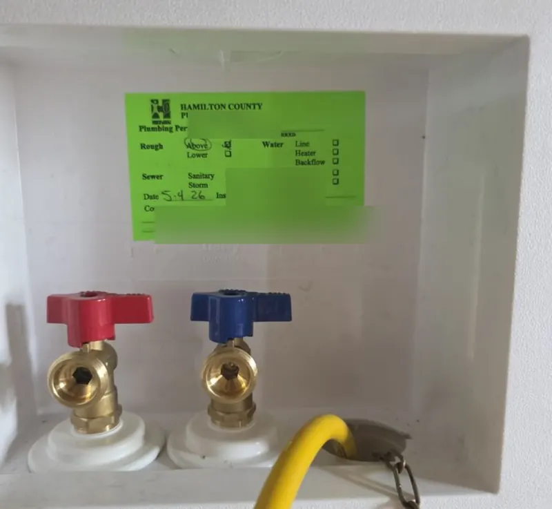 Recessed washer outlet box with hot and cold valves and a Hamilton County plumbing inspection tag