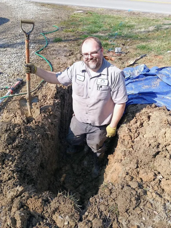 Mike Lipp standing in a hand-dug trench during a water line replacement
