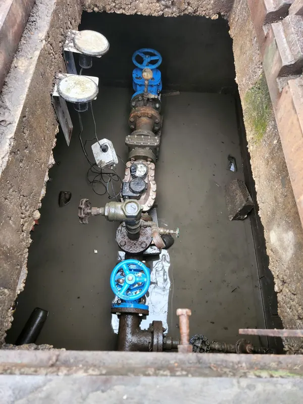 Water meter pit with a large water meter, blue gate valves and the backflow assembly on the service line