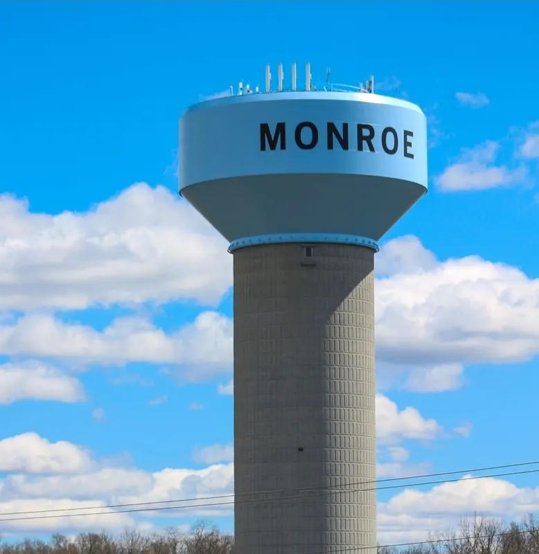 Monroe water tower against a blue sky with clouds