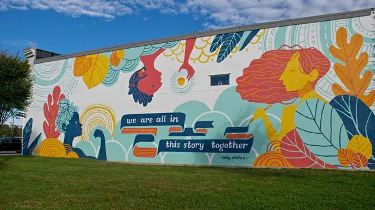 Colorful mural on a building wall with the words we are all in this story together, in Silverton