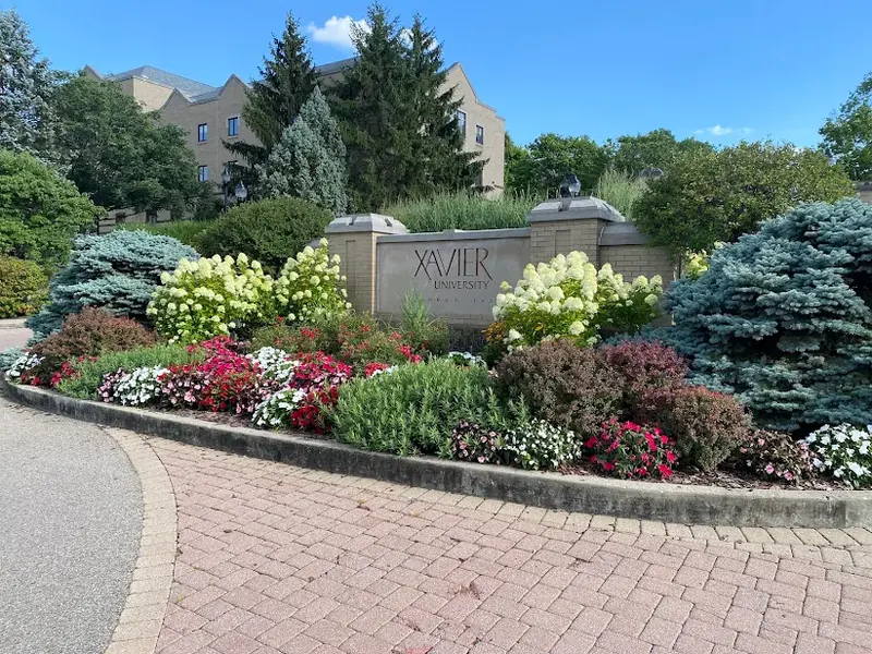 Xavier University entrance sign surrounded by colorful flower beds