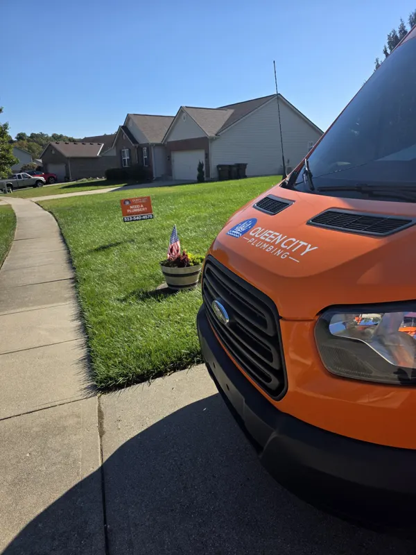 Queen City Plumbing yard sign with 513-540-4575 in a front lawn next to our service van